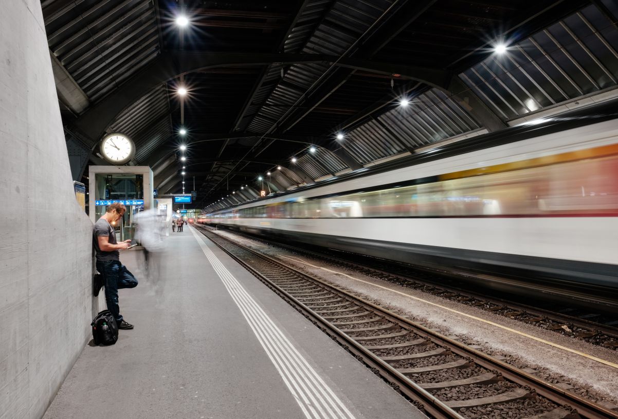 Man waiting on platform with train going past